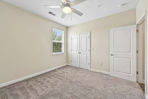 A bright Hawks Landing bedroom in Hickory NC featuring a ceiling fan and carpeted flooring