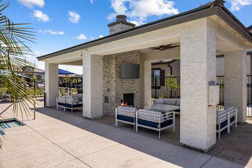 A patio with a stone fireplace and white furniture.