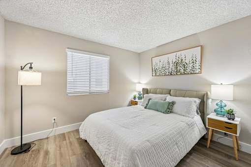 A bedroom with a bed, nightstand, and lamp.