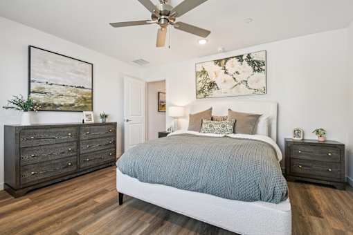A bedroom with a bed, dresser, and ceiling fan.