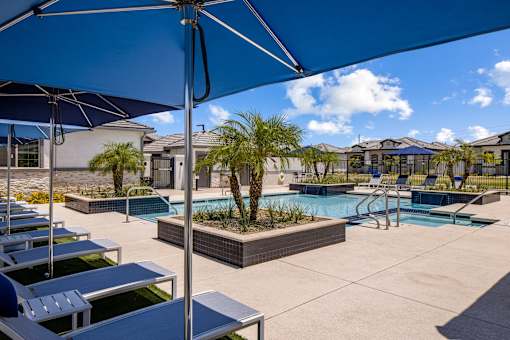 A pool area with sun loungers and a blue umbrella.