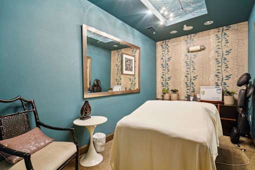 A room with a bed, chair, and mirror.