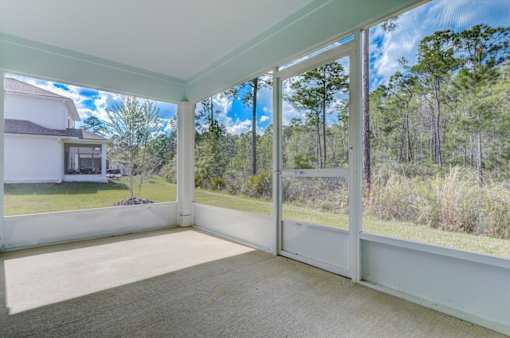 a screened in porch with a view of the woods