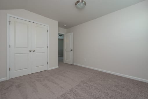 a bedroom with two doors and a carpeted floor