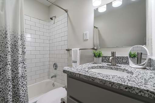 Bathroom at Idlewild 45 Apartments featuring granite vanity, modern fixtures, and tub-shower combination