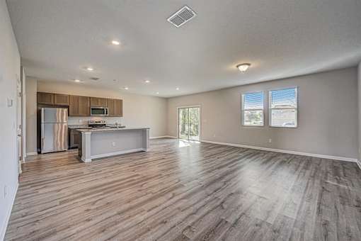 a spacious living room with a kitchen in the background