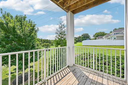 A wooden deck at Hawks Landing in Hickory NC with a white railing overlooking a green lawn and trees