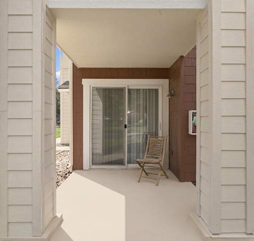 A patio with a chair and a sliding glass door.