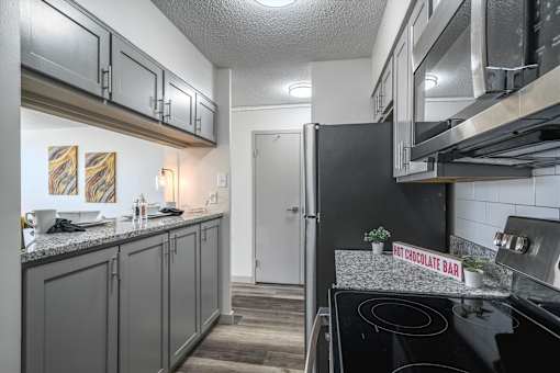 Modern kitchen at Idlewild 45 Apartments with stainless steel refrigerator, microwave, and granite countertops