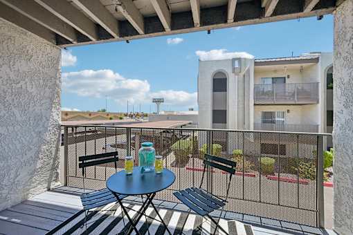 A balcony with a table and chairs overlooking a building.