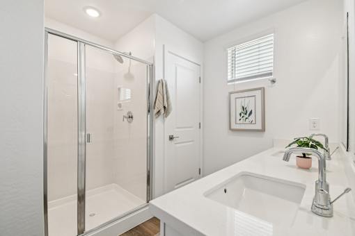 A white bathroom with a glass shower stall and a white sink.