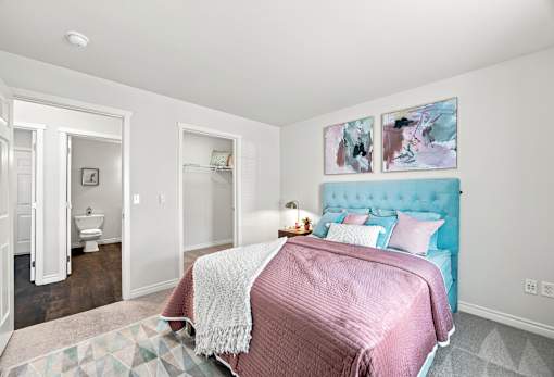 A bedroom with a bed, a rug, and two paintings on the wall.