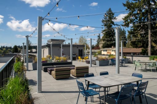 Two-Bedroom Apartments in Bothell, WA - Morado Bothell - Rooftop Deck with Various Seating Options, a BBQ Grill, Hanging Lights, and Landscaping