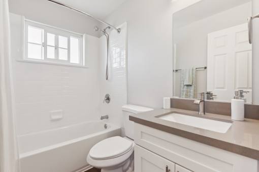 A white bathroom with a toilet, sink, and bathtub.