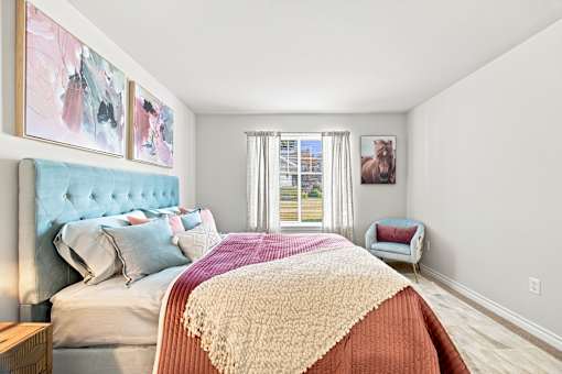 A bedroom with a large bed and a window with curtains.