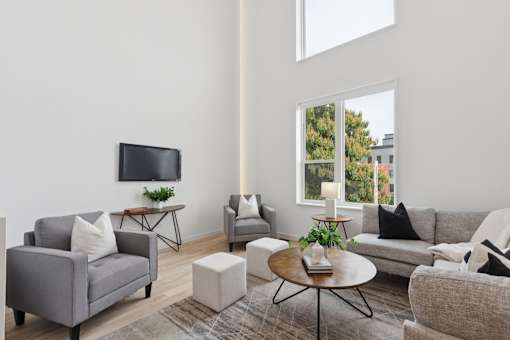 A living room with a grey couch, a white sofa, a coffee table, and a television.