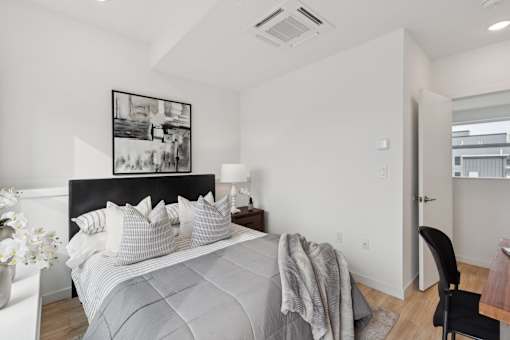 A bedroom with a bed, chair, and a picture on the wall.
