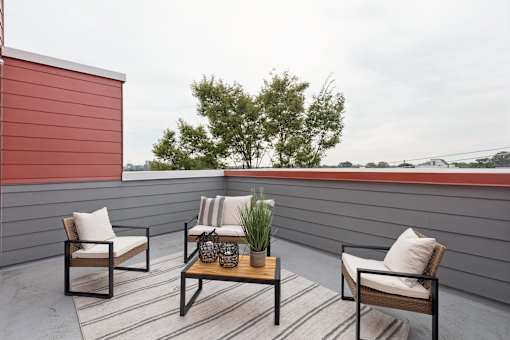 A patio with a table and chairs and a tree in the background.