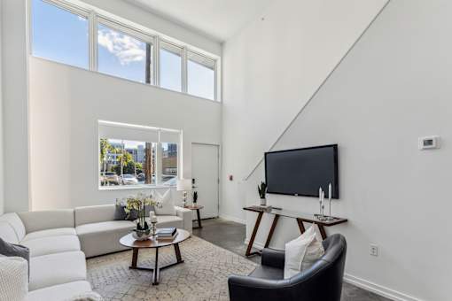 A living room with a white couch, a coffee table, and a flat screen TV.