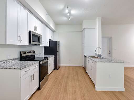 Spacious kitchen at Gateway Luxury Apartments featuring stainless-steel appliances and elegant granite countertops.