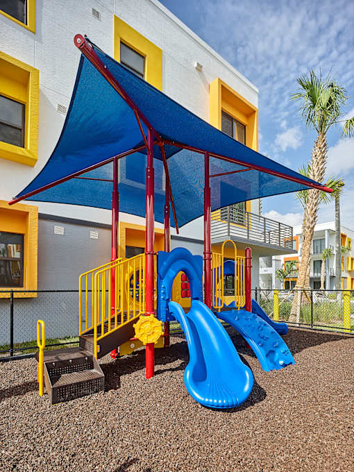 Outdoor playground at Gateway Luxury Apartments in Pompano Beach, featuring safe, modern play structures for children in a landscaped setting.