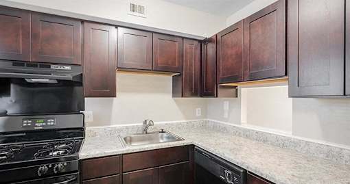A kitchen with dark wood cabinets and a black stove top oven.