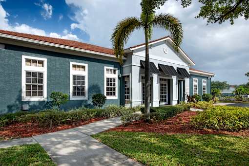 A blue house with a white trim and a palm tree in front.