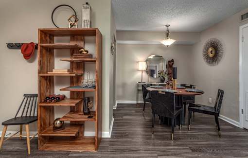 A room with a wooden shelf and a dining table.