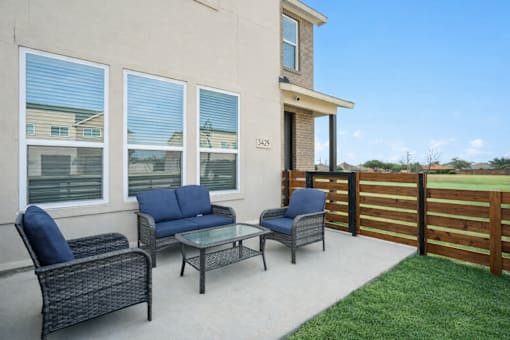 A patio with a couch, chair, and table outside a house.