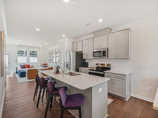 Modern open-concept kitchen with island and living room at The Maple 3-bedroom townhomes in Raleigh NC