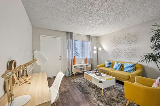 A living room with a yellow couch and a white chair.