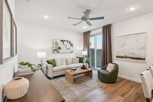 A living room with a white couch, a green armchair, a wooden coffee table, and a large painting on the wall.