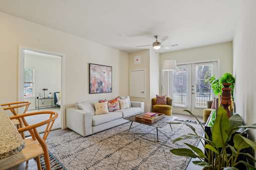 A living room with a white couch, a rug, and a ceiling fan.