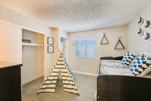 A room with a bed, a dresser, and a striped rug.