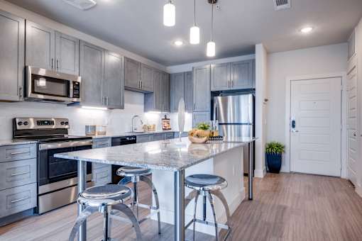 A modern kitchen with a large island and stainless steel appliances.