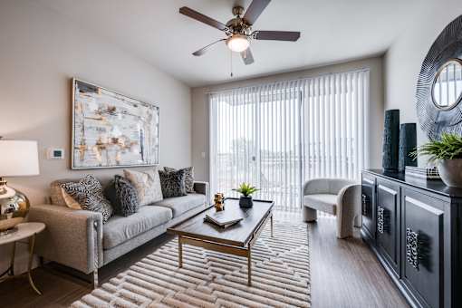 A living room with a grey couch, a coffee table, and a ceiling fan.