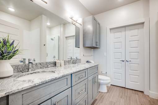 A bathroom with a sink, mirror, toilet and cabinet.