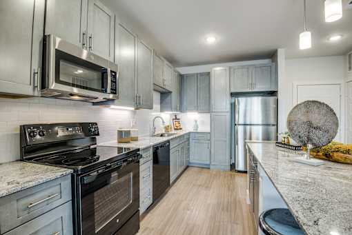 A modern kitchen with stainless steel appliances and wooden flooring.