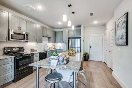 A modern kitchen with a table and chairs in the middle.