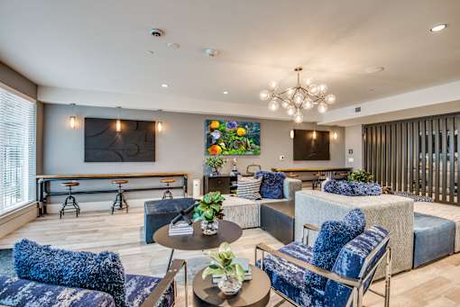 A living room with blue chairs and a painting on the wall.