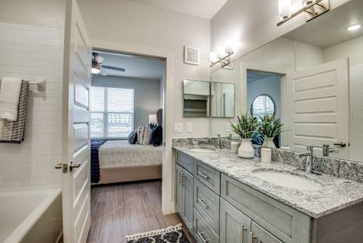 A bathroom with a white tub, sink, and mirror.