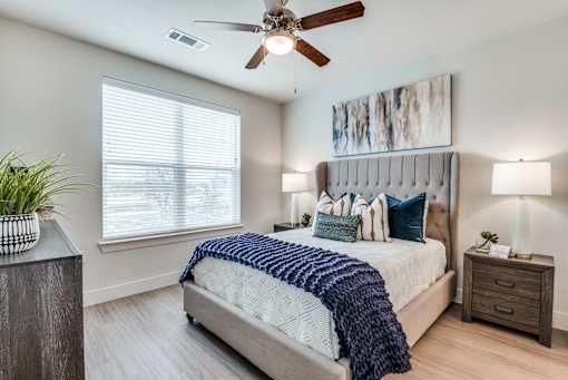 A bedroom with a bed, a ceiling fan, and a window.