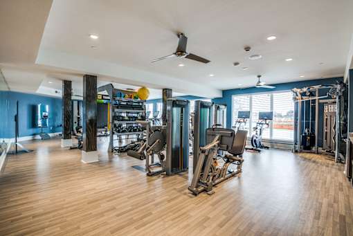 A gym with a variety of equipment including treadmills, weights, and exercise machines.