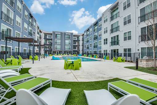 A pool surrounded by lounge chairs in a courtyard.