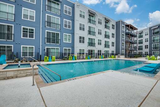 A swimming pool in front of a multi-story apartment building.