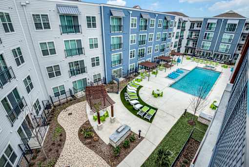 A view of a pool and patio area from a balcony of a building.