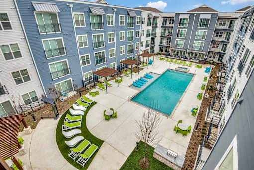 A large swimming pool surrounded by a grassy area and lounge chairs.