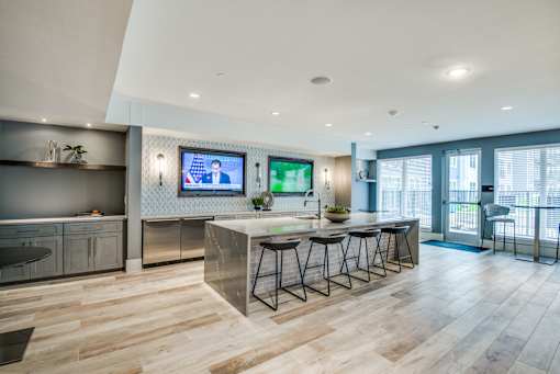 A modern kitchen with a bar area and a television mounted on the wall.