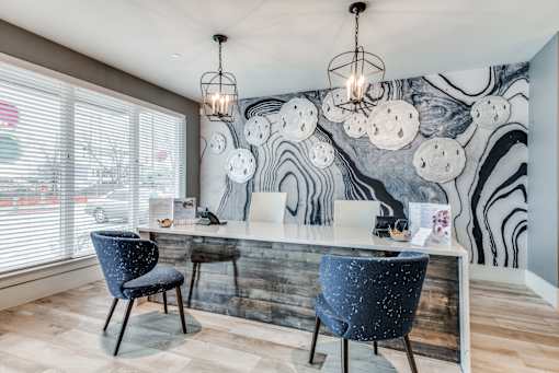 A modern office with a zebra print wallpaper and two blue chairs.