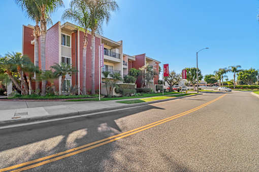 A street view of a residential area with apartment buildings and palm trees.